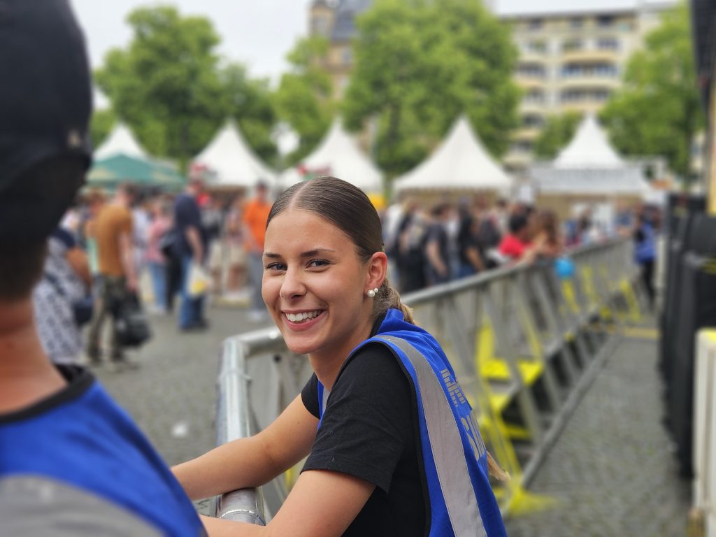 Sicherheitsmitarbeiterin lächelt in die Kamera bei Mannheimer Stadtfest. Bühnengraben
